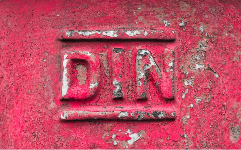 Altes DIN-Logo auf rotem Metall gestanzt.